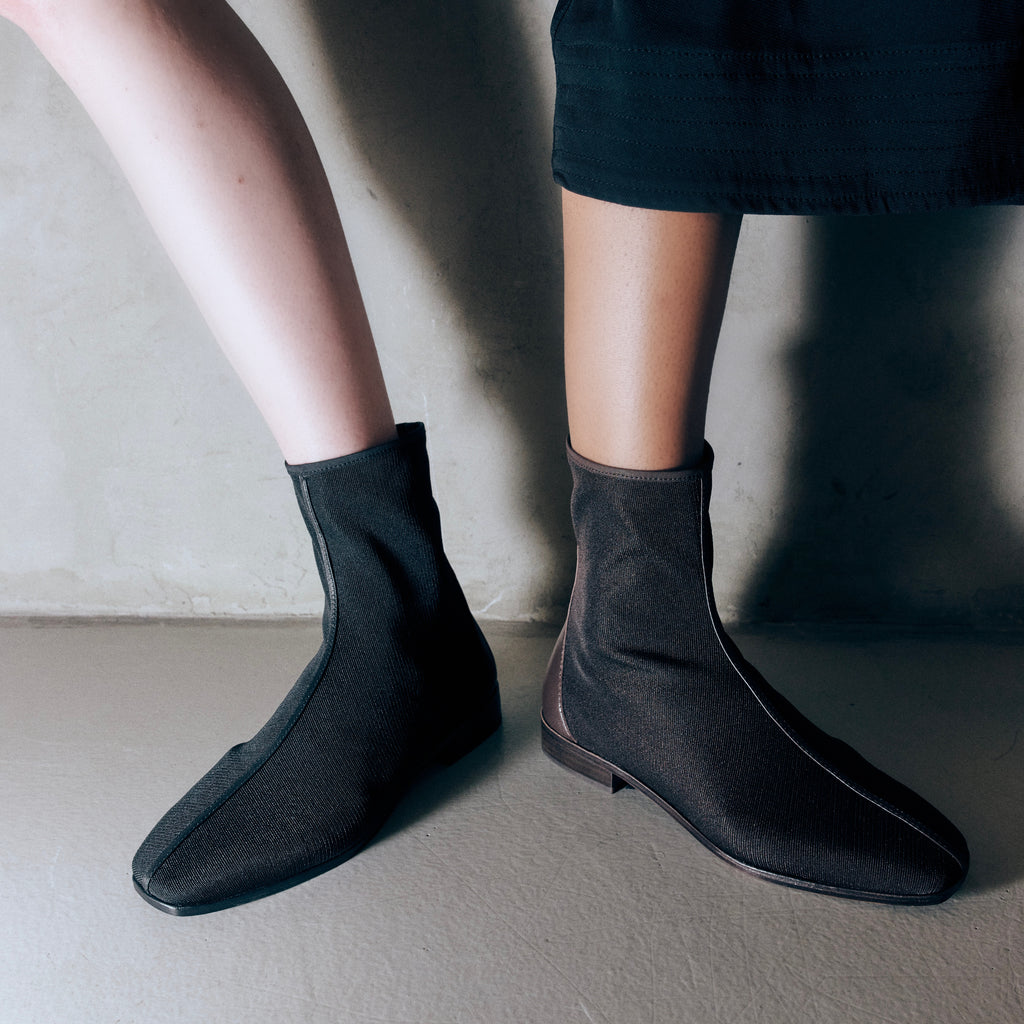 Model wearing Aliza Mesh Bootie in brown, styled with a skirt to show its lightweight and versatile ankle boot look.