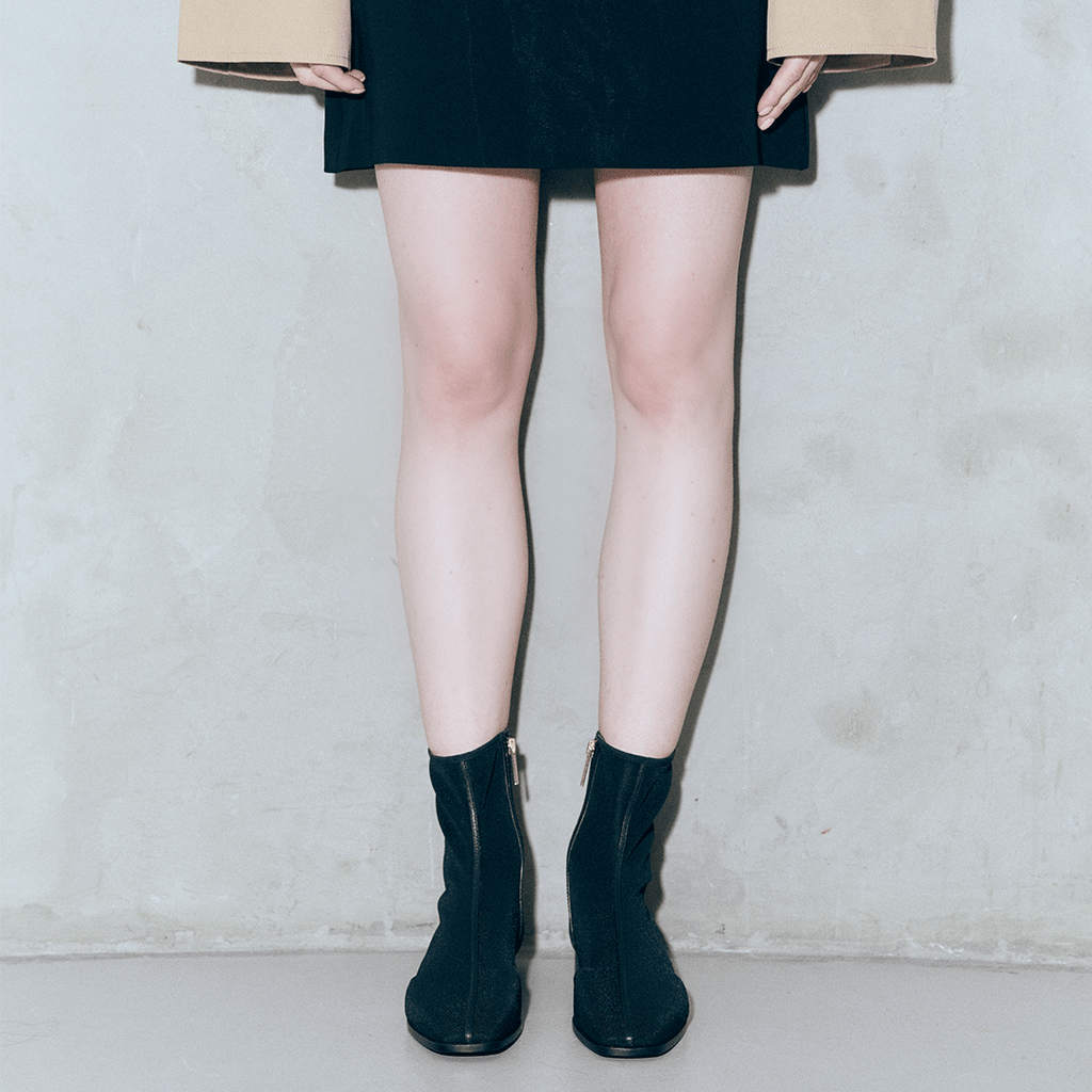 Model standing in Aliza Black boots with legs centered, styled with a skirt for a chic everyday look.