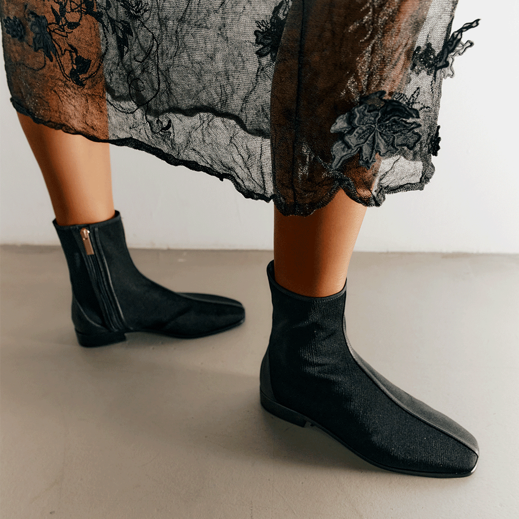 Close-up of Aliza Black boots styled with lace skirt, blending elegance with modern edge.