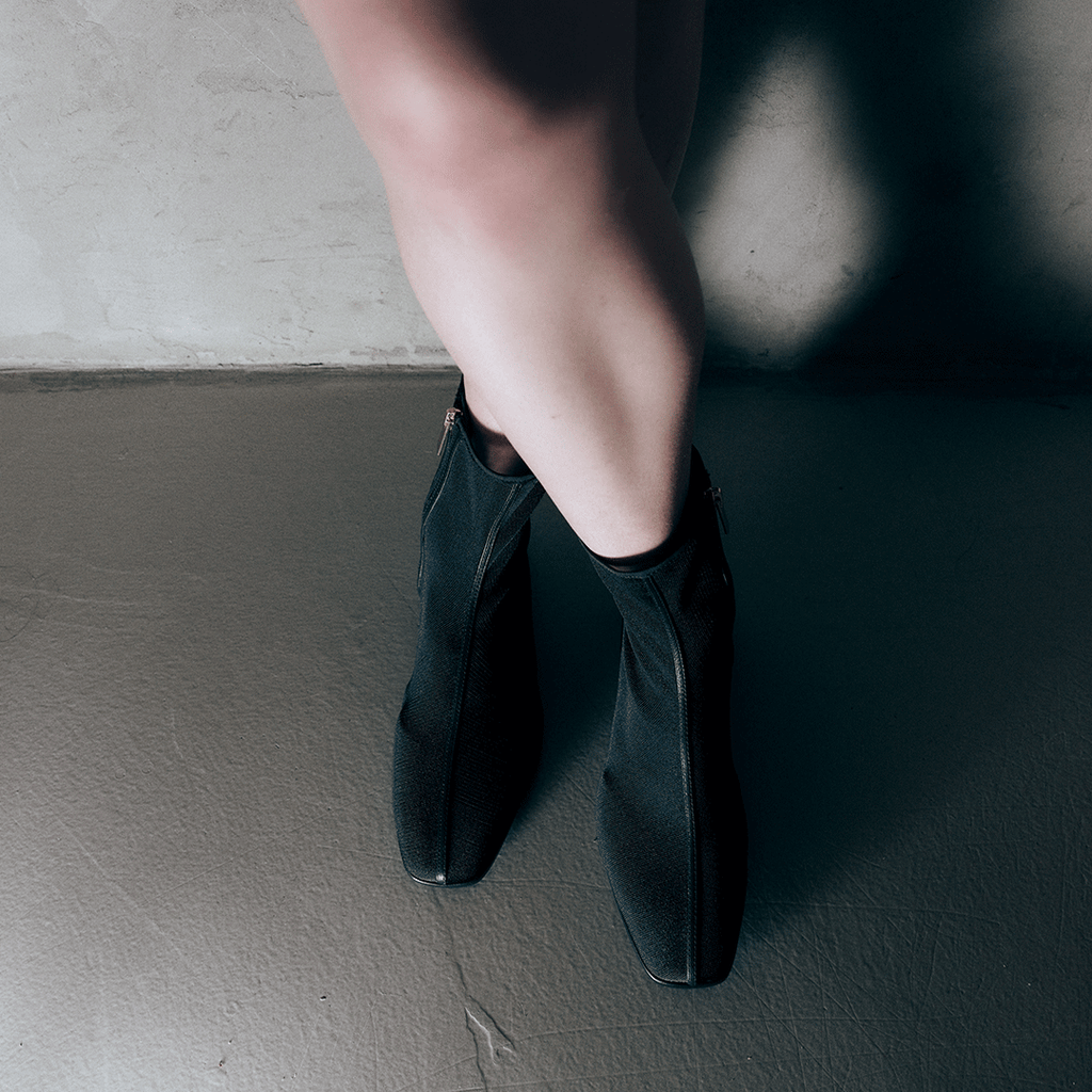Movement shot of model stepping in Aliza Black boots, emphasizing flexible and comfortable fit.