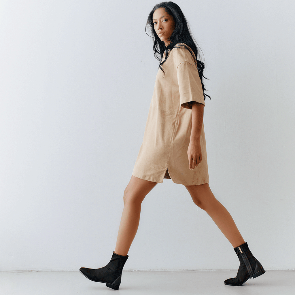 Lifestyle shot of model walking in Daniella Shevel Aliza Brown flat boots with a beige dress, styled for effortless chic.