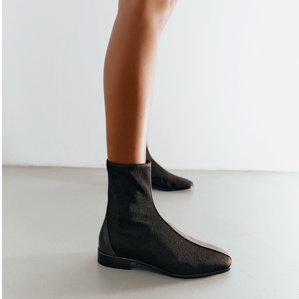 Model wearing Aliza Brown boots styled with a skirt, showcasing their versatile everyday flat boot design.