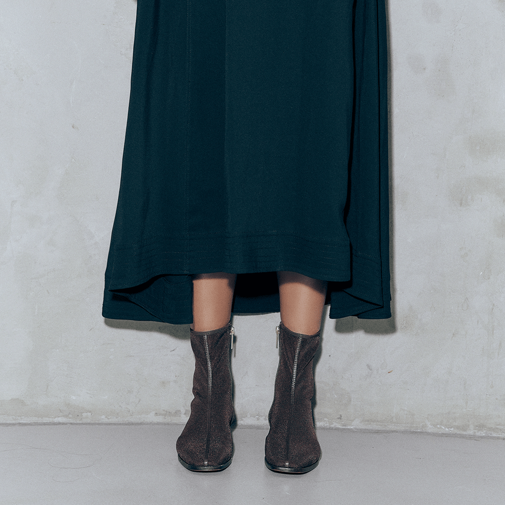 Front-facing shot of Aliza Brown boots styled with a skirt, highlighting minimal yet refined design.
