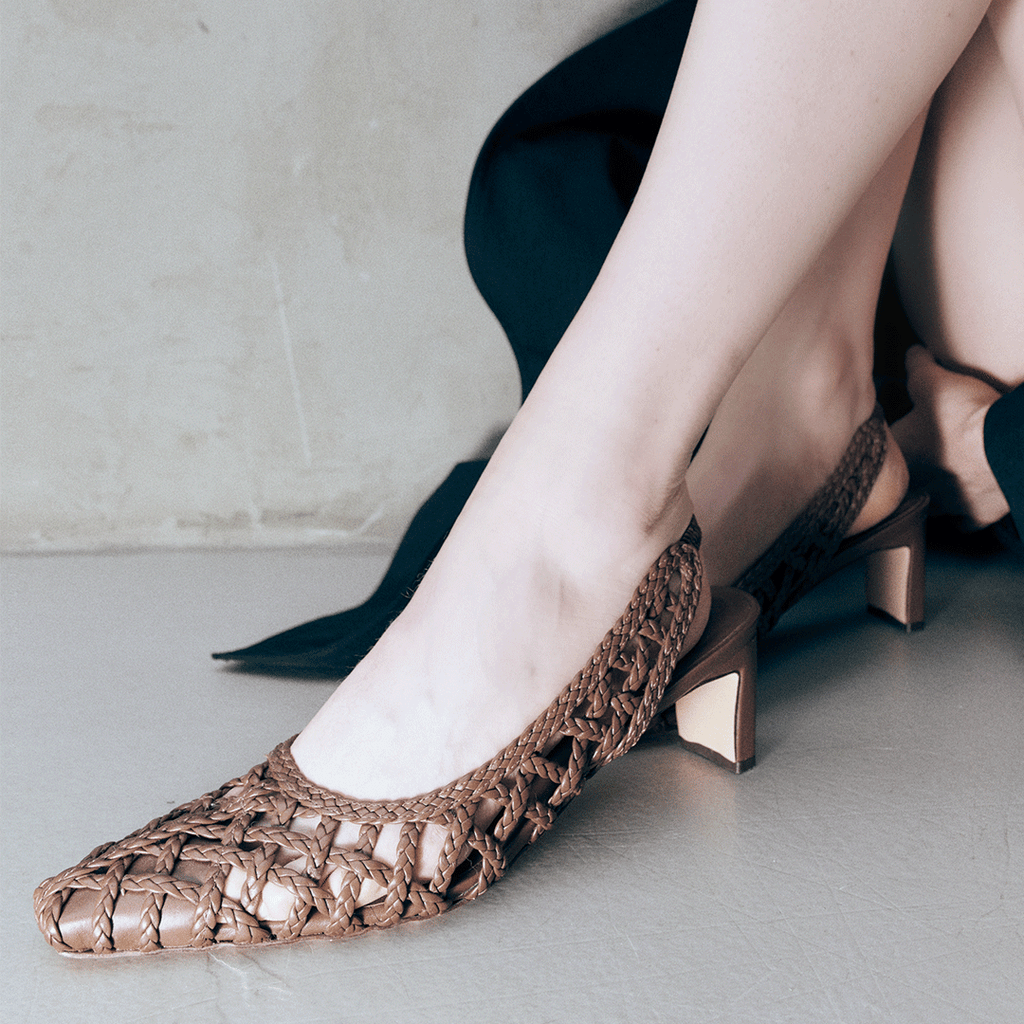 Close-up side view of Daniella Shevel's Cora slingback heel in brown, highlighting the intricate handwoven leather and gold-accented block heel.

