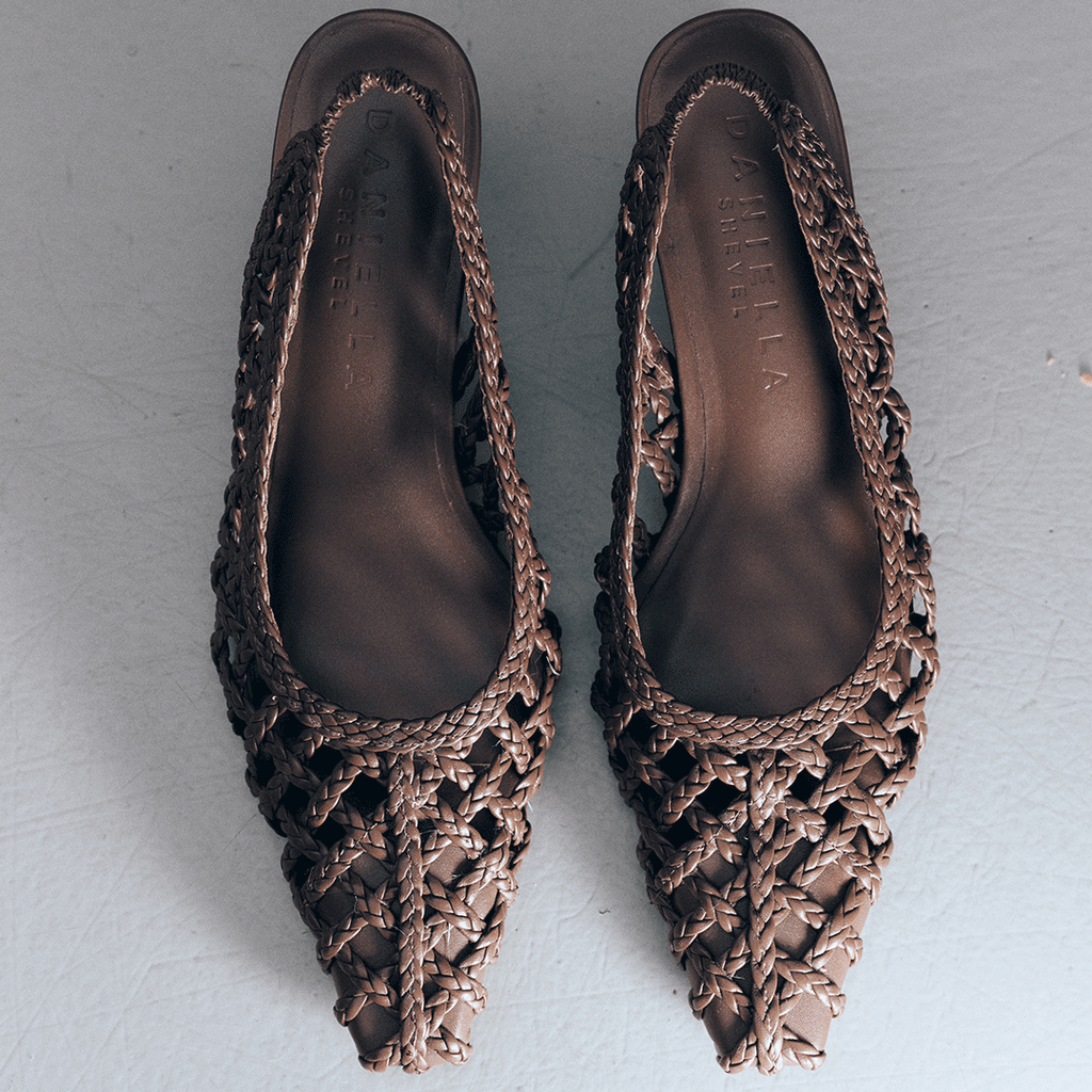 Top-down flat lay of the Daniella Shevel Cora slingback heels in brown, showing the detailed woven leather and pointed silhouette.

