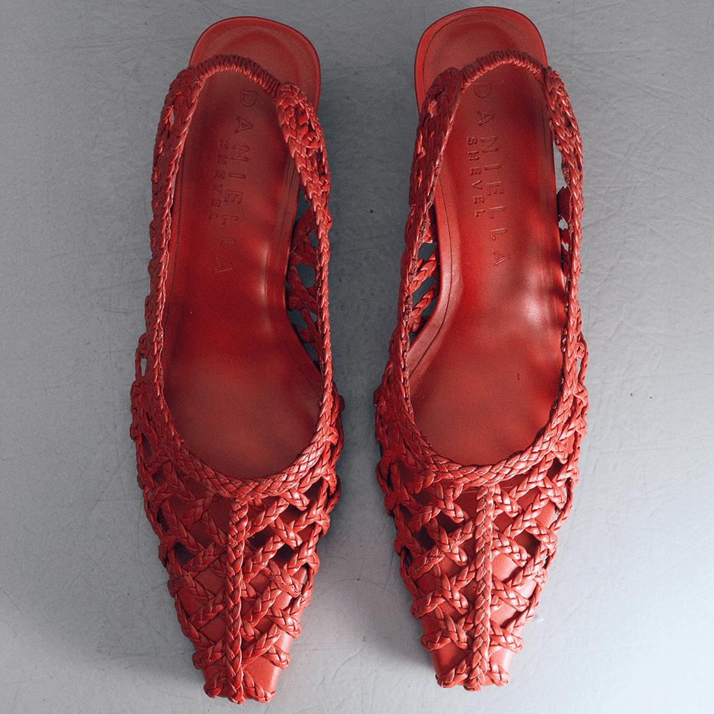 Top-down flat lay of Cora slingback heels in vibrant red braided leather, emphasizing the intricate woven craftsmanship.

