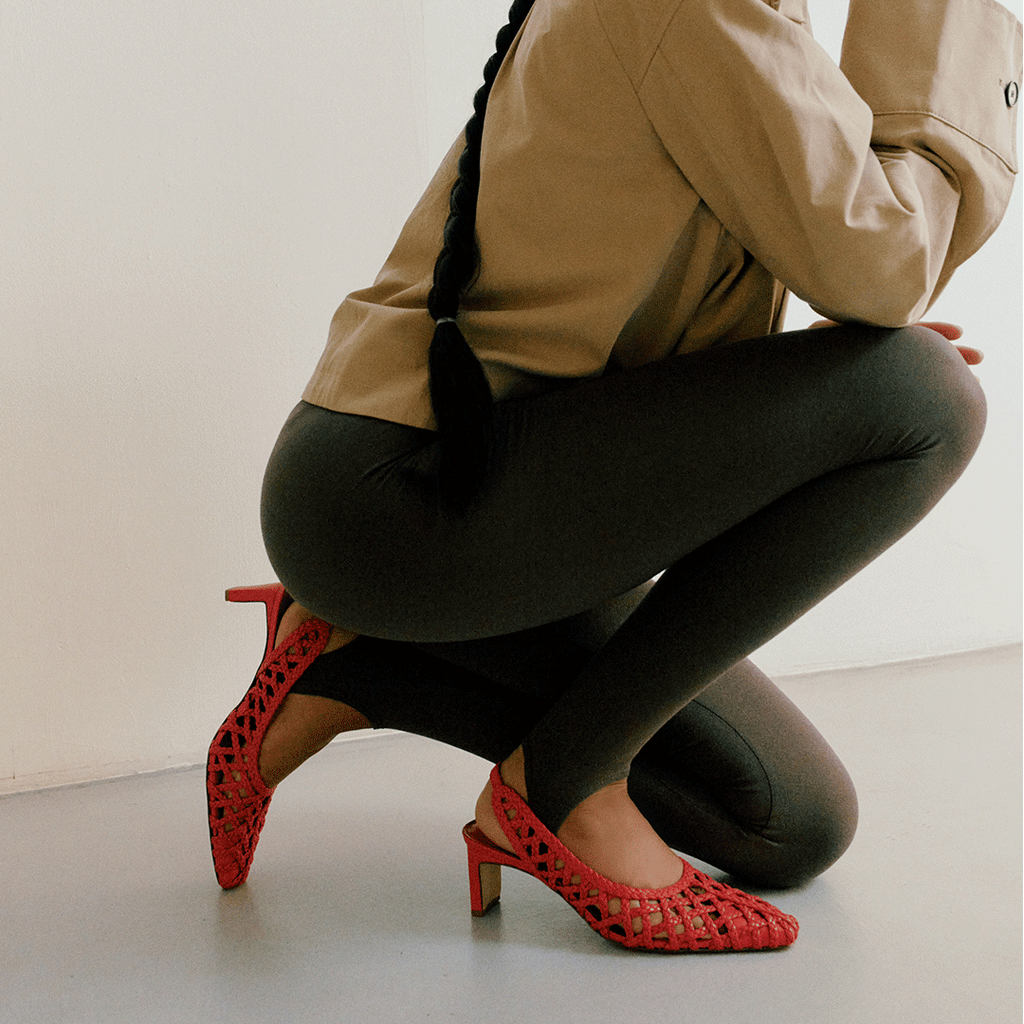 Lifestyle image of Cora red slingback heels worn while crouching, pairing modern comfort with elevated style.

