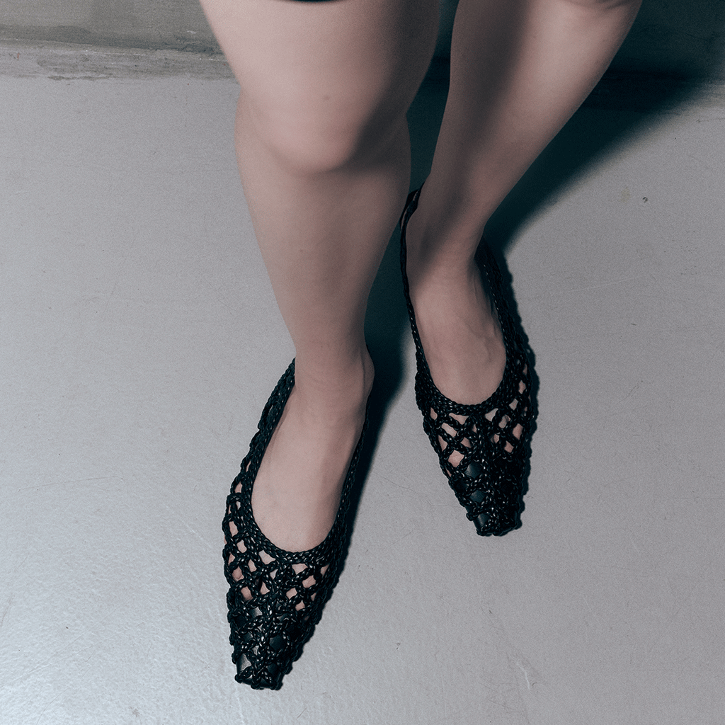 Close-up of model wearing Daniella Shevel Halo Black flats – showcasing pointed toe and intricate woven leather texture.