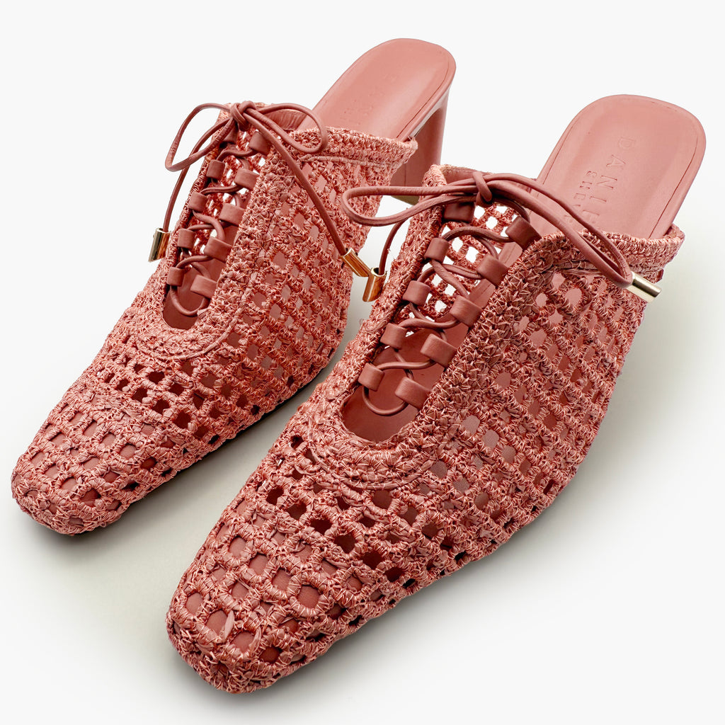 Angled studio shot of Daniella Shevel Bruna raffia heel mules in Berry Petal, highlighting the sculpted heel, airy handwoven design, and elegant almond-pink color from side perspective.