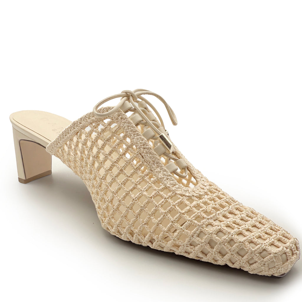 Side studio image of Daniella Shevel Lina raffia mule in Wild Straw – showcasing open-back silhouette, mid-height heel, and artisan woven leather.