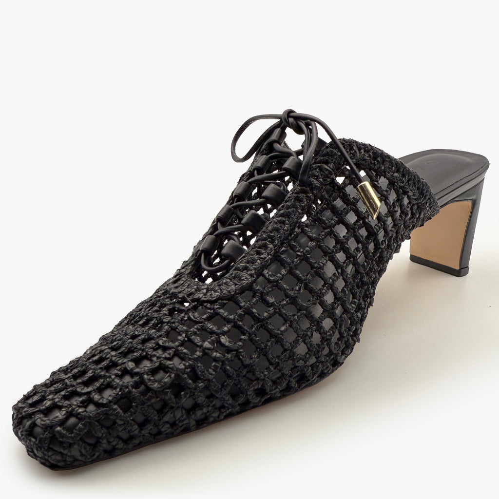 Side studio view of black Daniella Shevel raffia mule – highlighting sculpted mid heel, open back, and woven raffia craftsmanship.