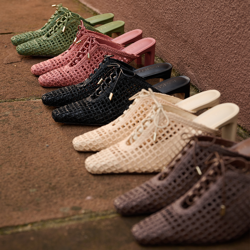  Daniella Shevel Lina woven heels stacked in layers—black, raffia, pink, green, and chestnut—emphasizing texture, craftsmanship, and color variety.
