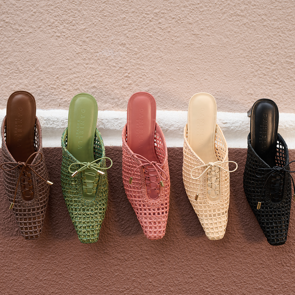 Front view of Daniella Shevel Lina lace-up raffia heels in a hanging arrangement, featuring Wild Straw and complementary tones styled on a soft neutral wall.
