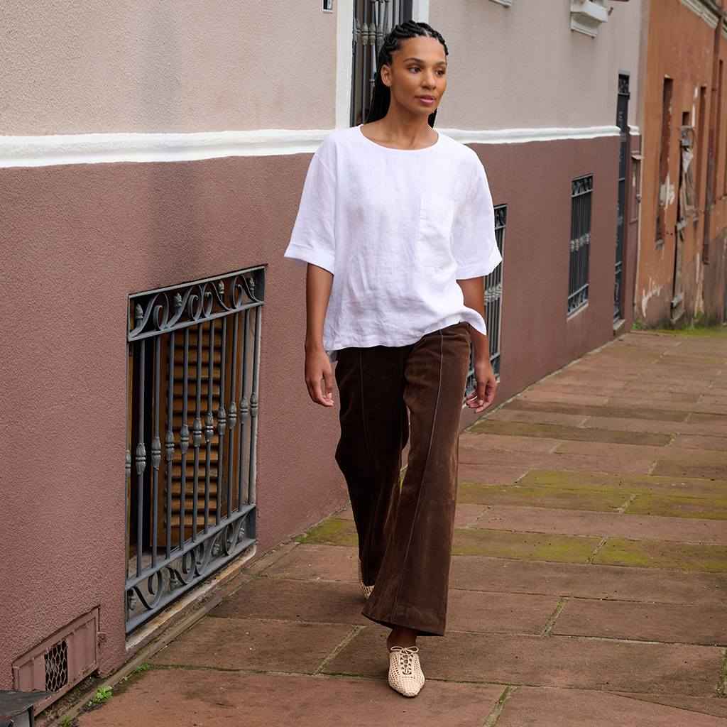 Model walks effortlessly in Daniella Shevel Lina raffia mule in Wild Straw, styled with oversized white tee and wide-leg trousers for relaxed sophistication.