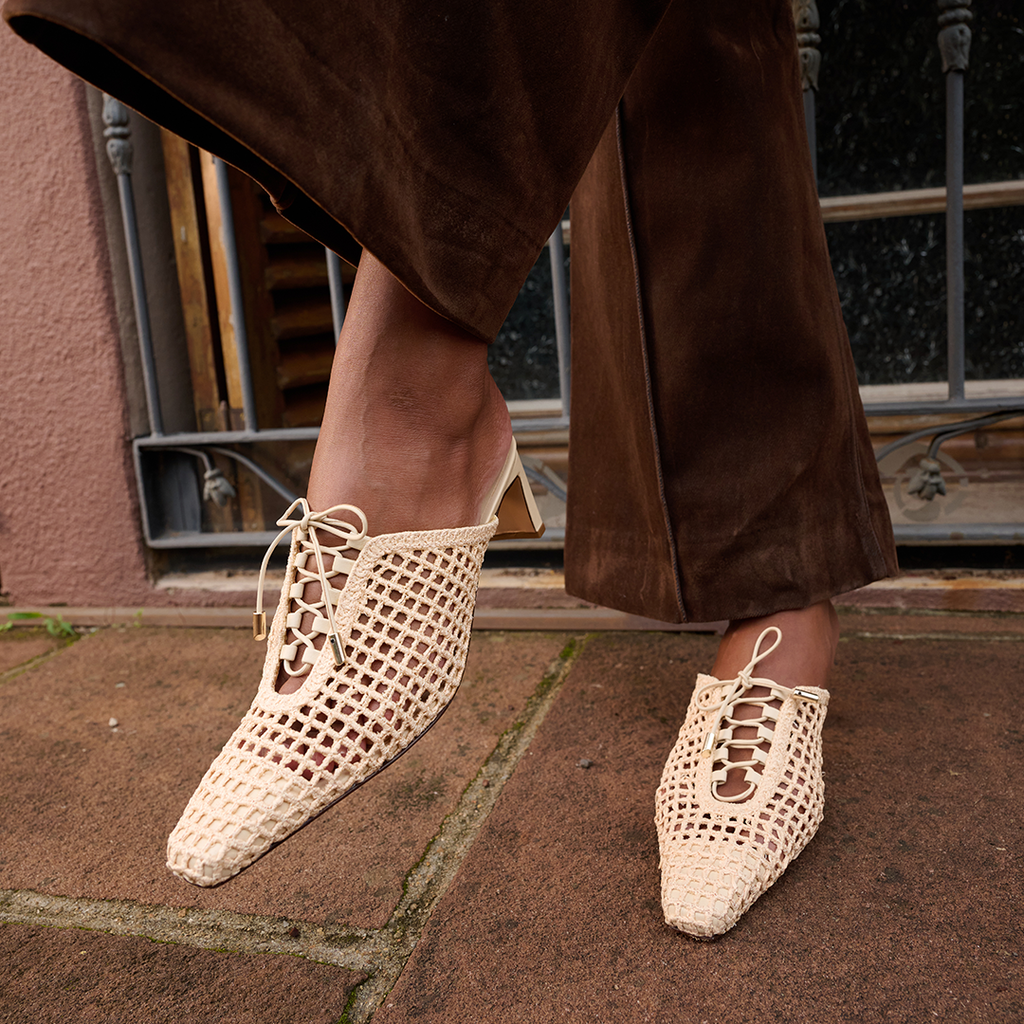 Daniella Shevel Lina raffia heels in Wild Straw  styled with chocolate brown trousers for an elevated street-style moment that highlights the shoe’s sculpted heel and handwoven mesh design.