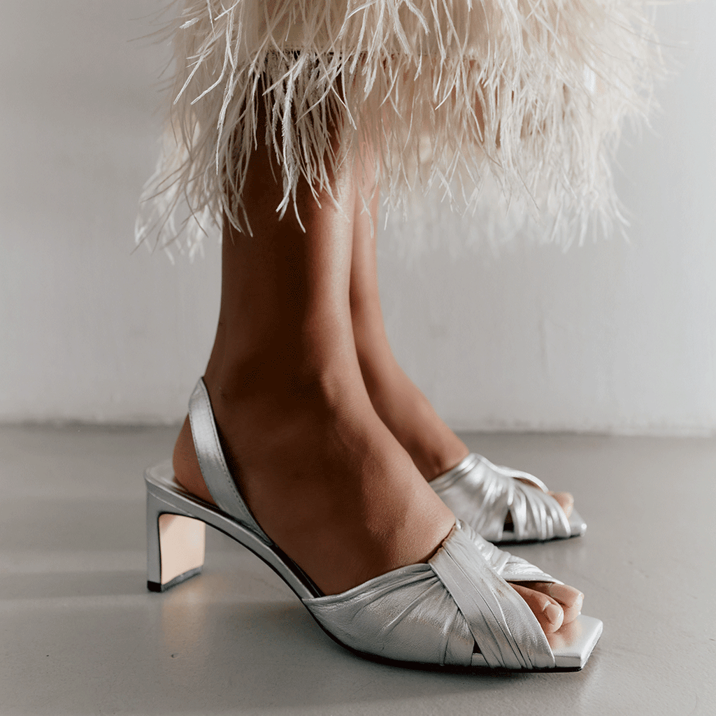 Riley silver sandals styled in chic neutral-toned outfit with movement.