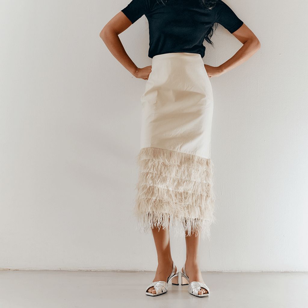 Studio walking capture of Riley Leather Low-Heel in silver paired with ivory skirt.