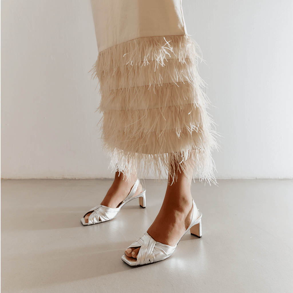 Riley silver sandals styled with minimalist skirt look in studio.