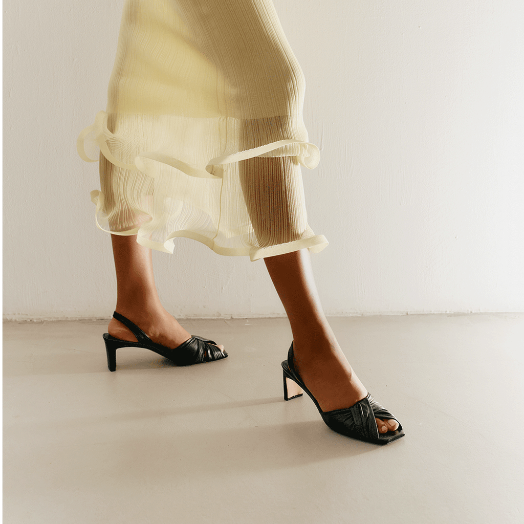 Riley black sandals styled with cropped neutral dress for minimal elegance.