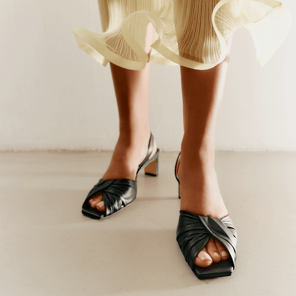 Riley black sandals styled with cropped trousers in studio scene.