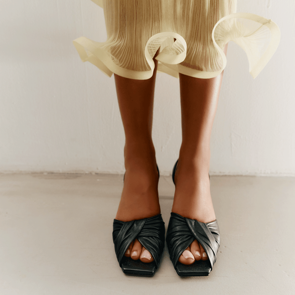 Flat-lay view of Riley black sandals with sculptural leather straps.