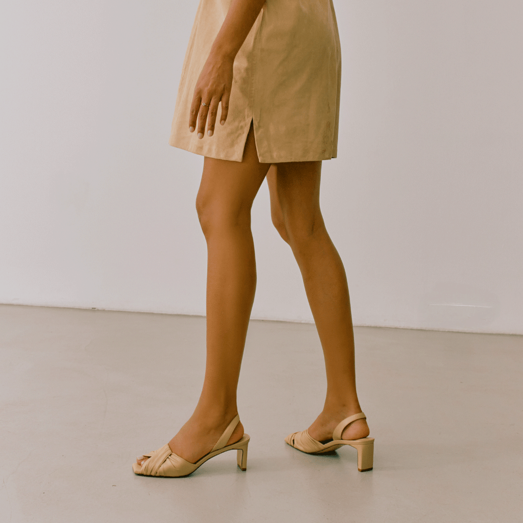 Model walking in Riley soft oat sandals styled with cream outfit.