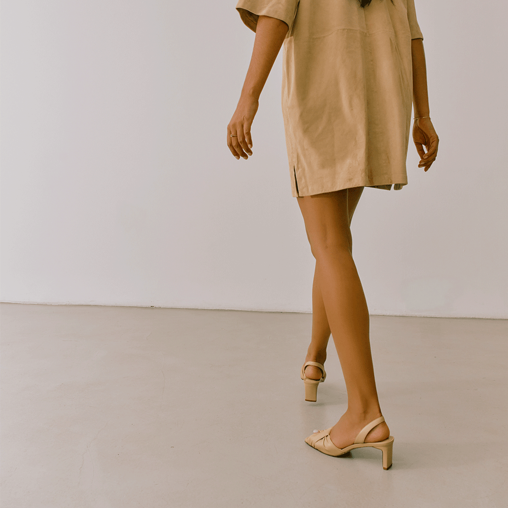 Studio walking capture of Riley soft oat sandals styled with minimal beige look.