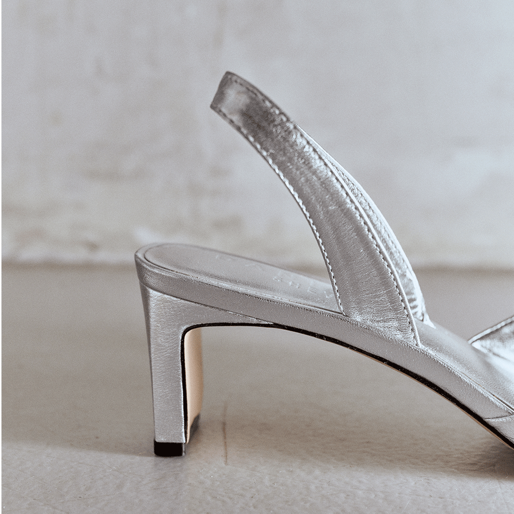 Angled side shot of Riley silver sandals showcasing heel height.