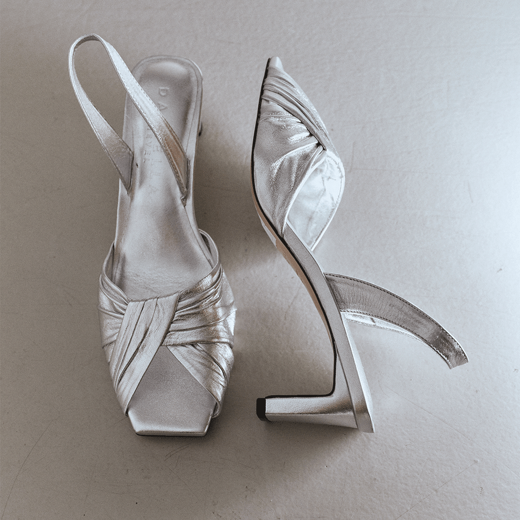 Studio pair shot of Riley silver sandals against minimal backdrop.