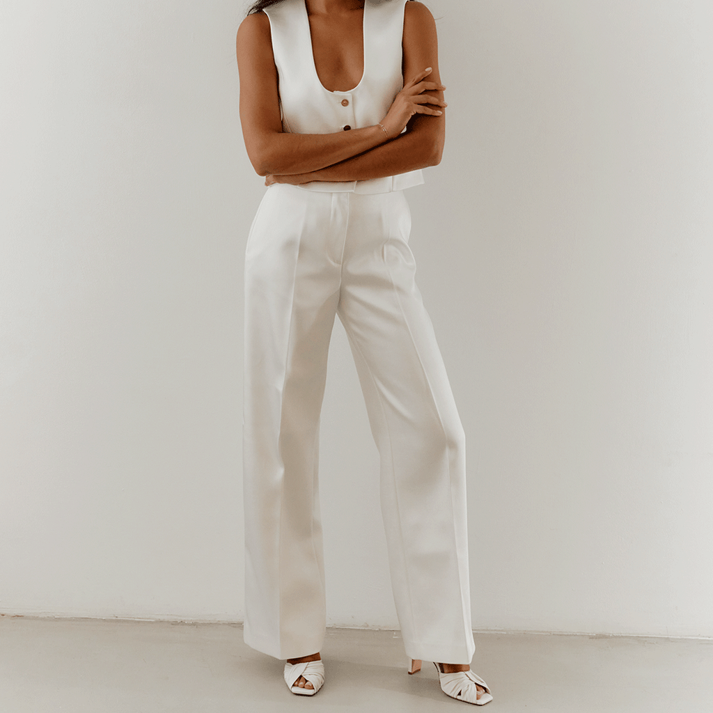 Lifestyle capture of white Skyler slingbacks styled with wide-leg trousers.