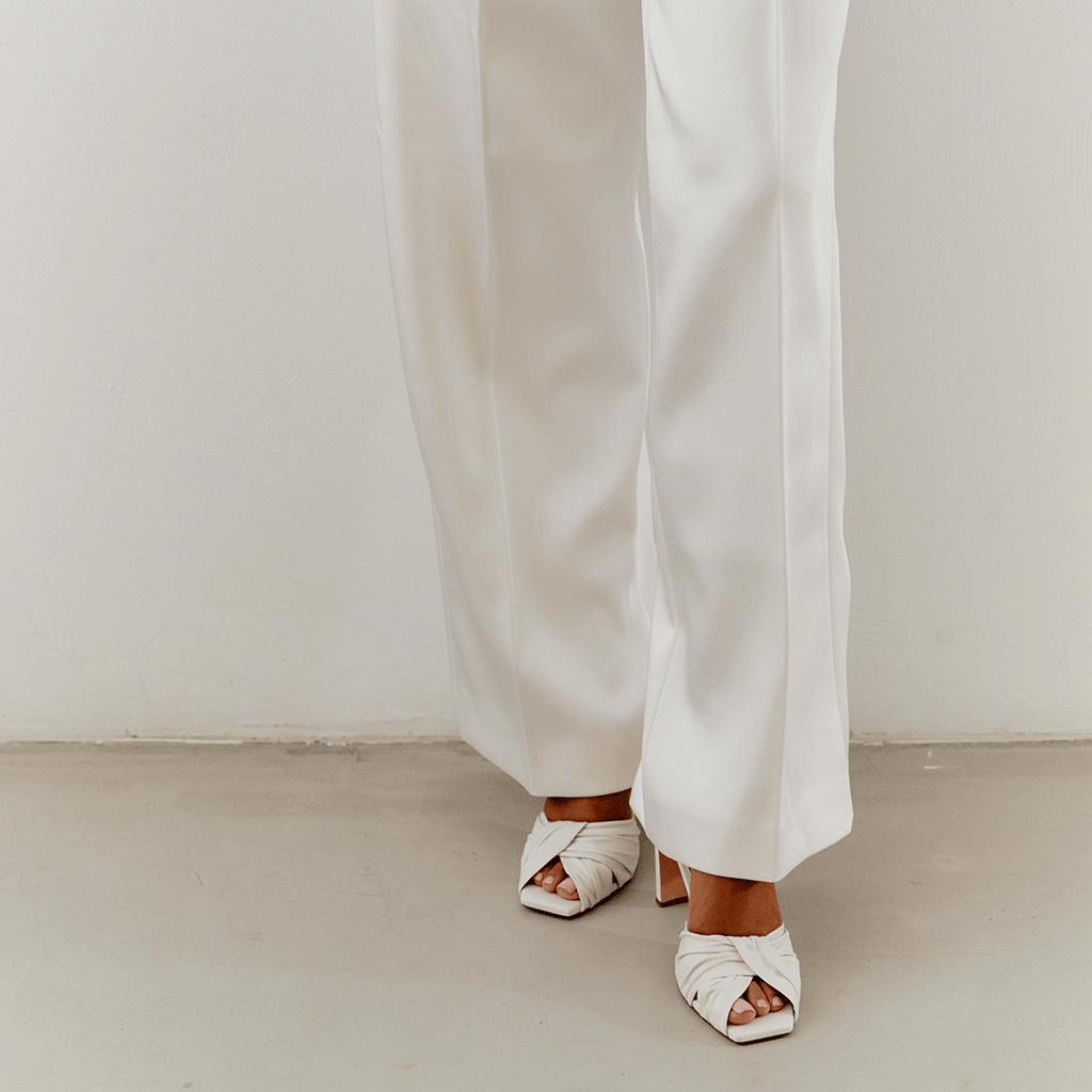 Lifestyle photo of white Skyler high-heel slingbacks styled with pants.