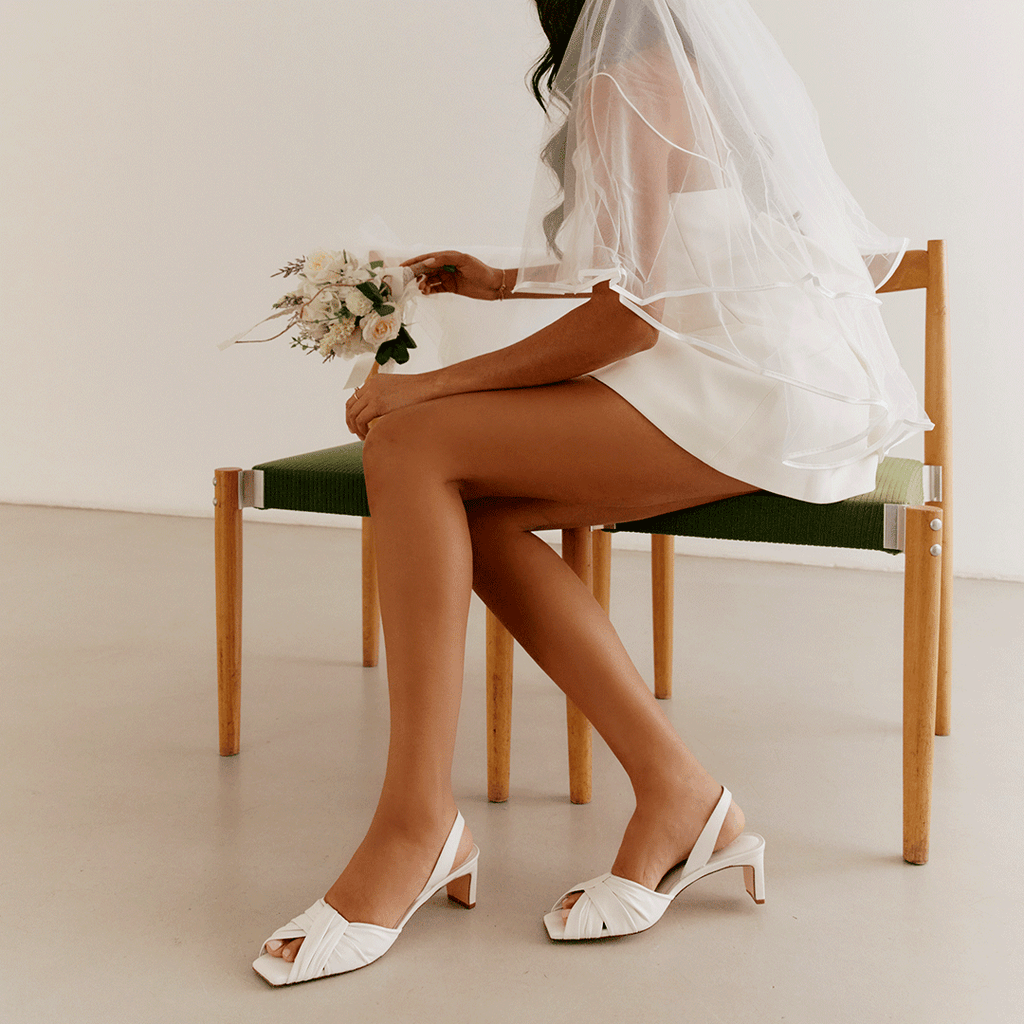 Flat-lay of Riley Leather Low-Heel in white paired with flowers.