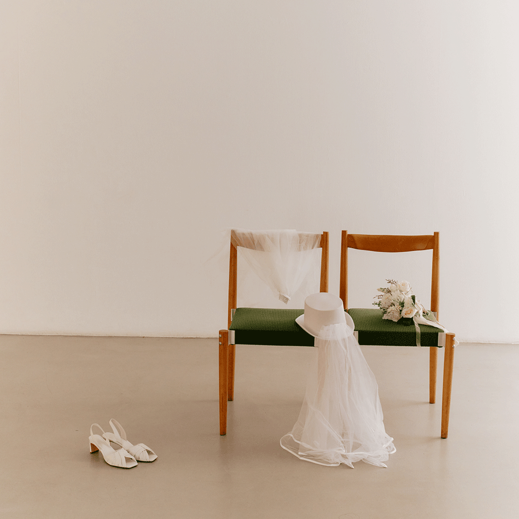 Minimalist studio capture with Riley white sandals styled near a bench.