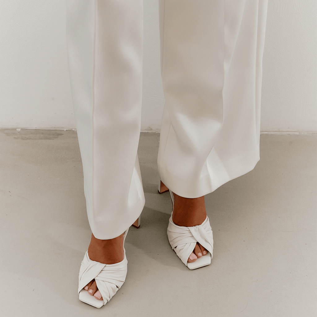 White Skyler heels styled with soft cream trousers, lifestyle photo.