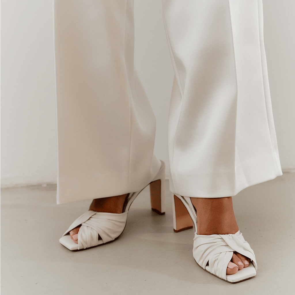 White Skyler leather slingback heels styled with wide-leg pants, front view.