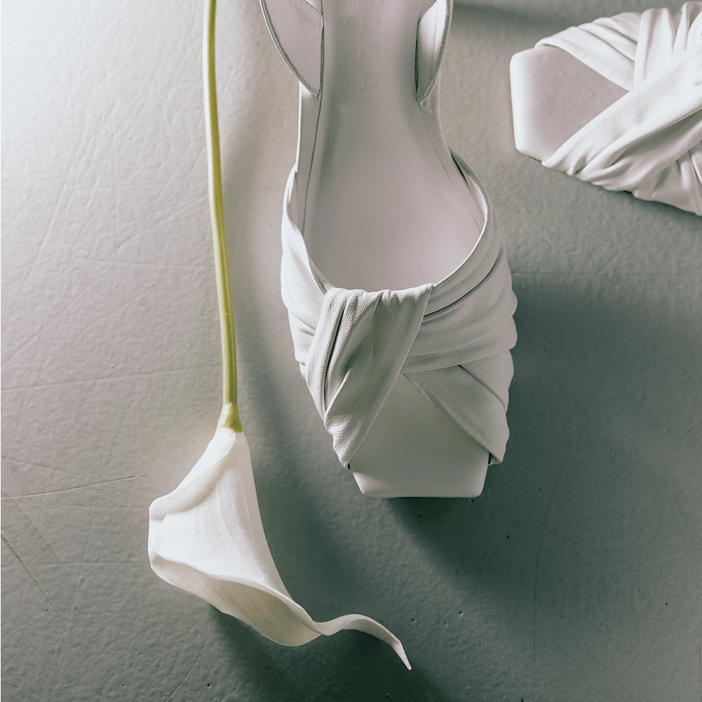 Riley white sandals styled with soft draped dress in a studio setup.