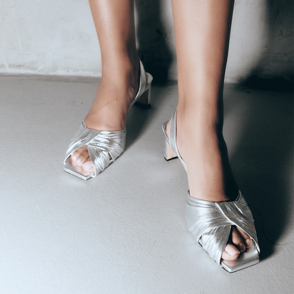Detailed close-up of Riley silver sandal straps highlighting metallic shine.