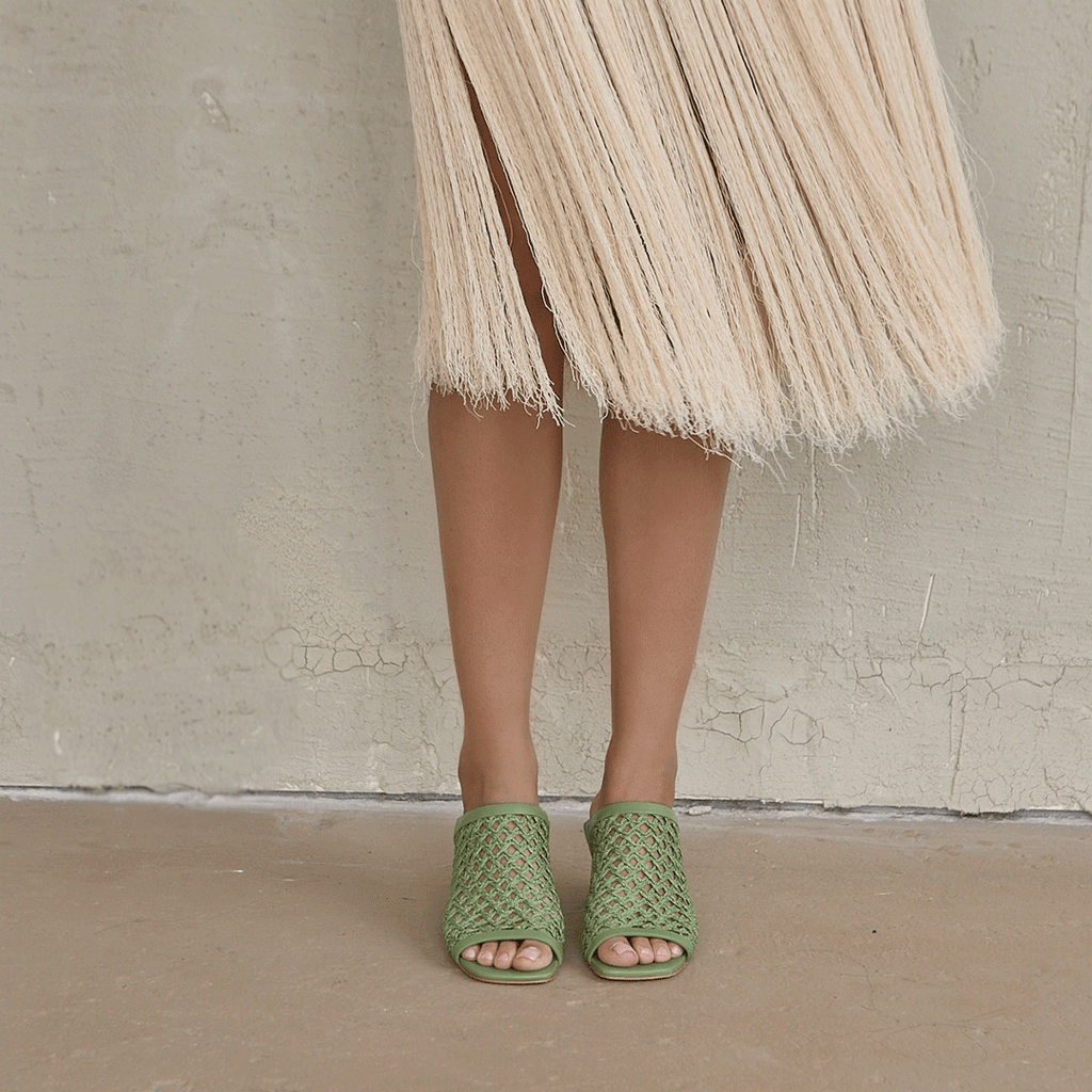 Casual lounge pose in a modern setting, showcasing the stylish and breathable design of the Daniella Shevel woven mule.