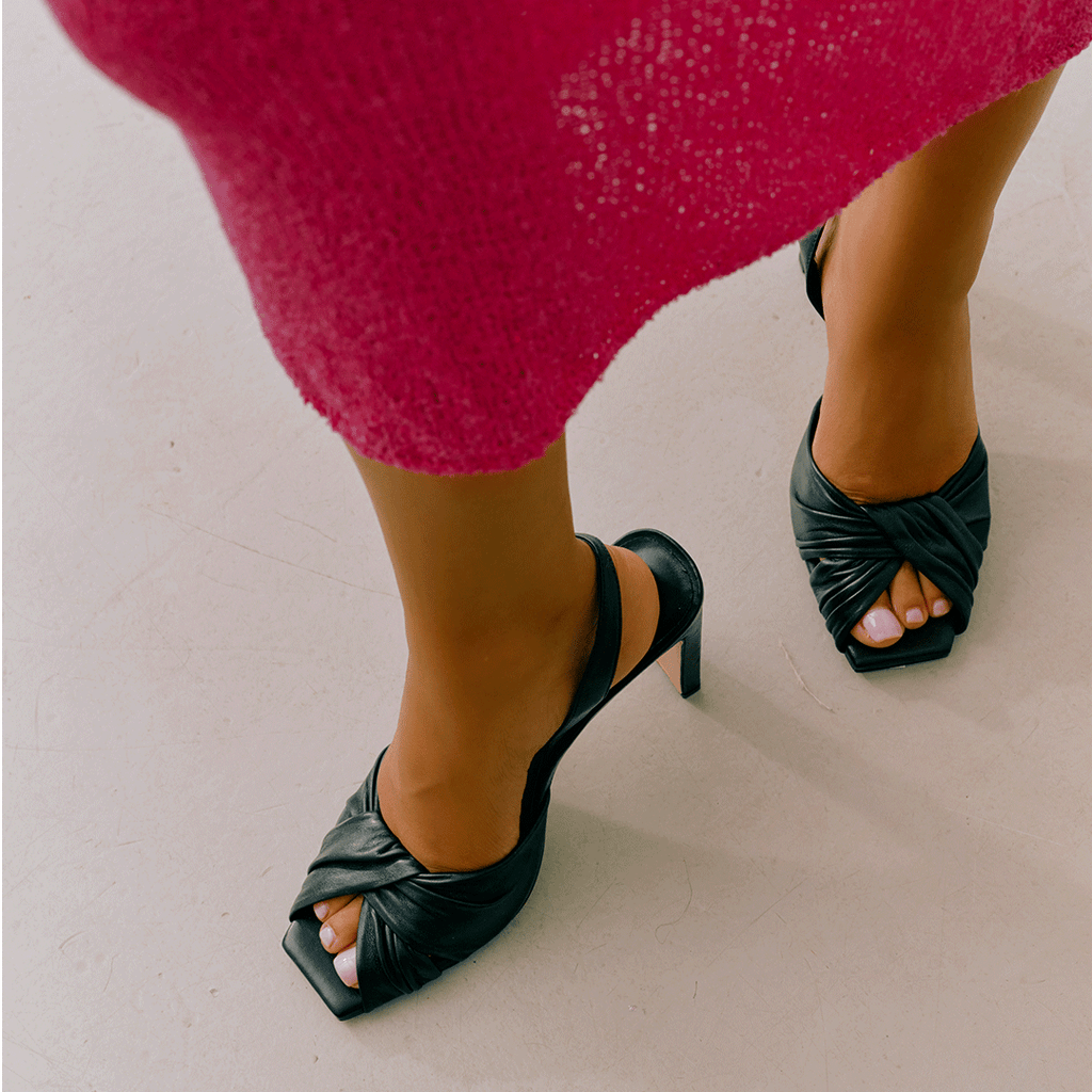 Lifestyle styling of black Skyler slingbacks with pink fitted skirt.