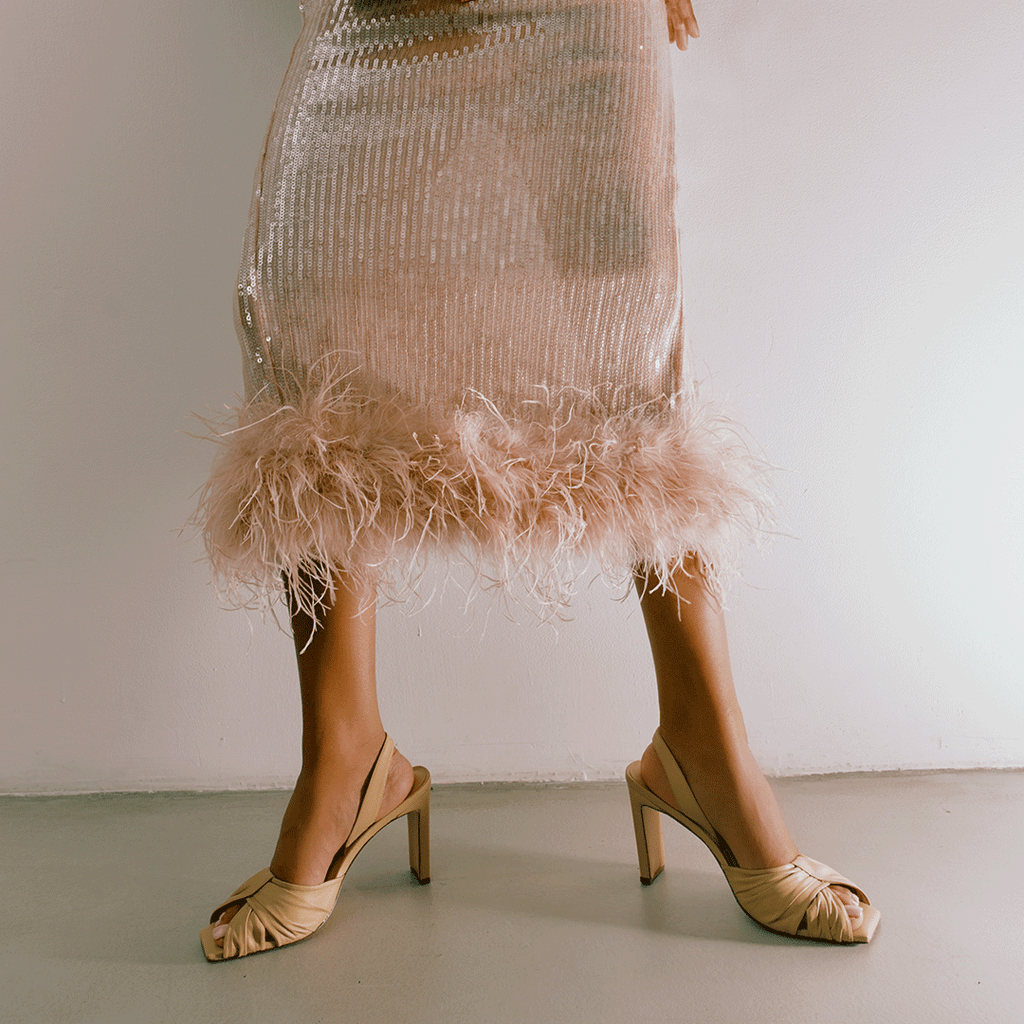 Skyler leather high-heel in soft oat with feather hem outfit, lifestyle capture.
