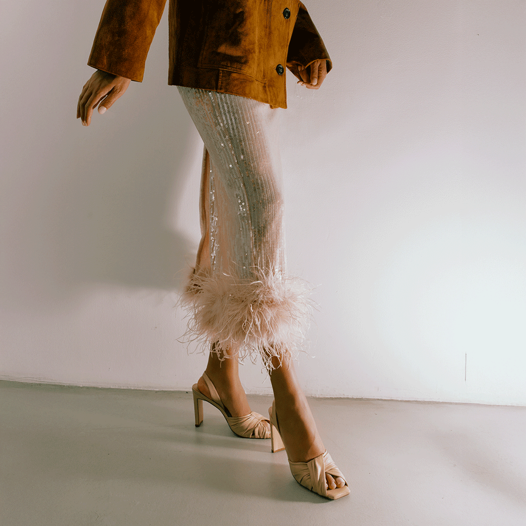 Lifestyle capture of soft oat Skyler slingbacks with pleated skirt.