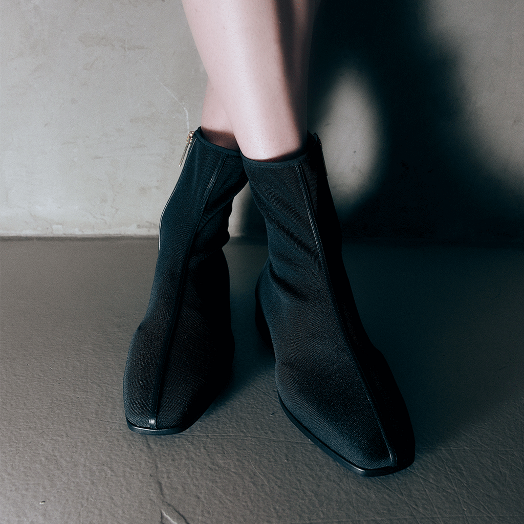 Three-quarter back view of Aliza Black boots on model, highlighting the curved heel and elegant fit.