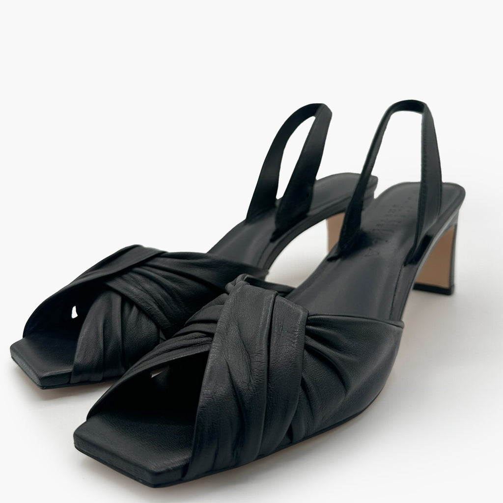 Side angled studio shot of Riley Leather Low-Heel in black styled with minimal backdrop.