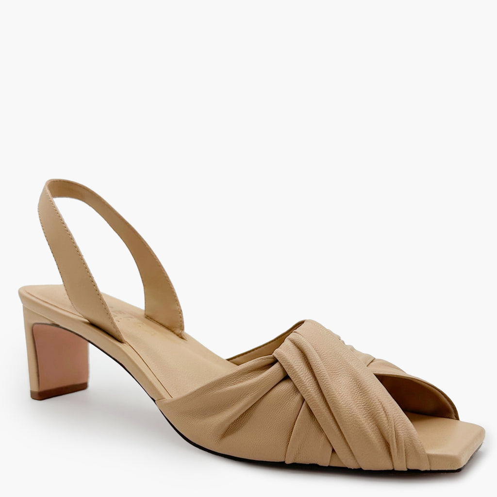 Side angled studio shot of Riley Leather Low-Heel in soft oat styled with dress.