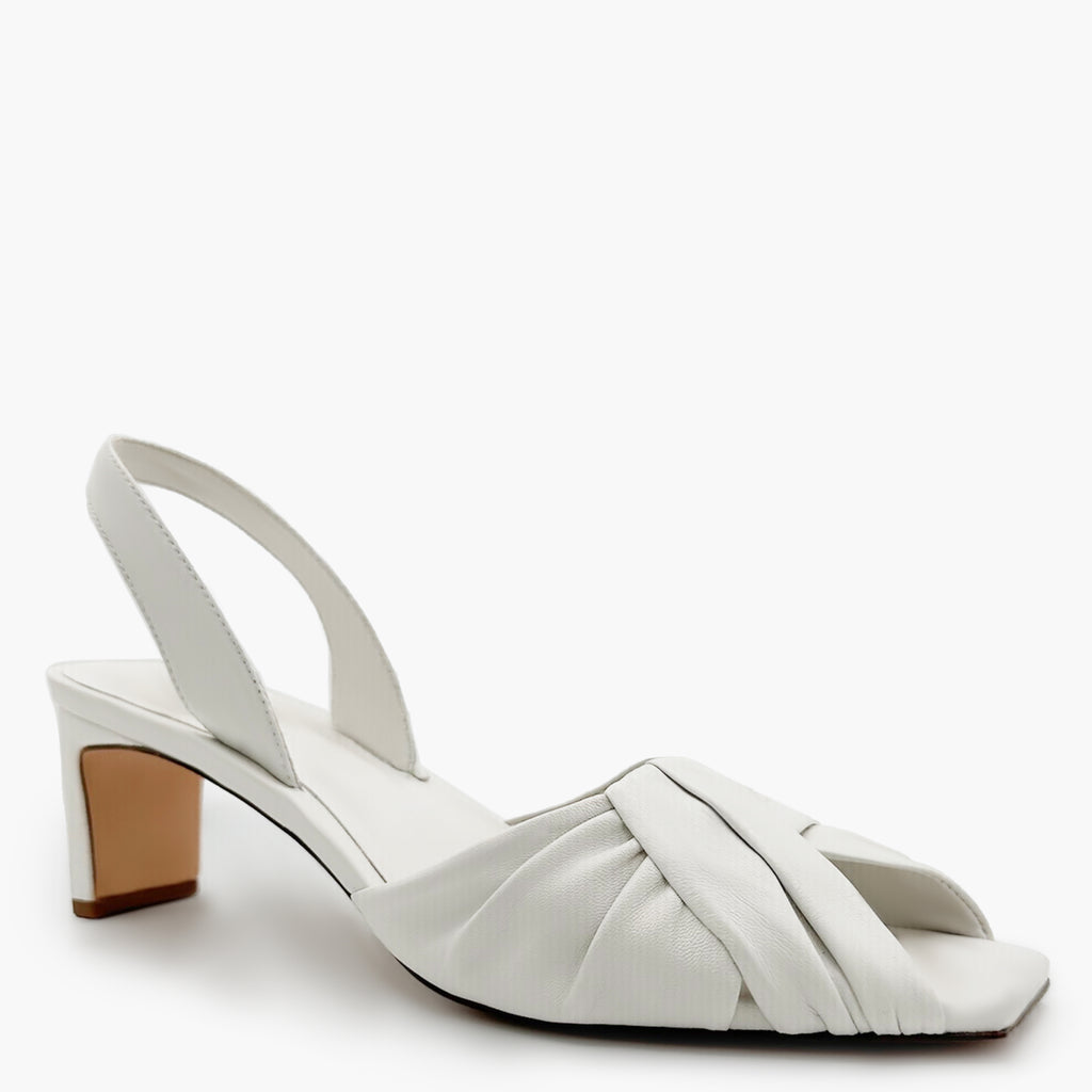 Studio flat-lay of Riley white sandals with sculptural straps.