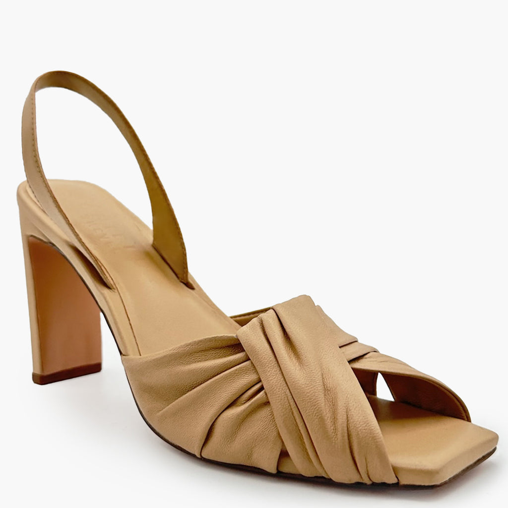 Close-up lifestyle photo of soft oat Skyler heels with pleated dress.