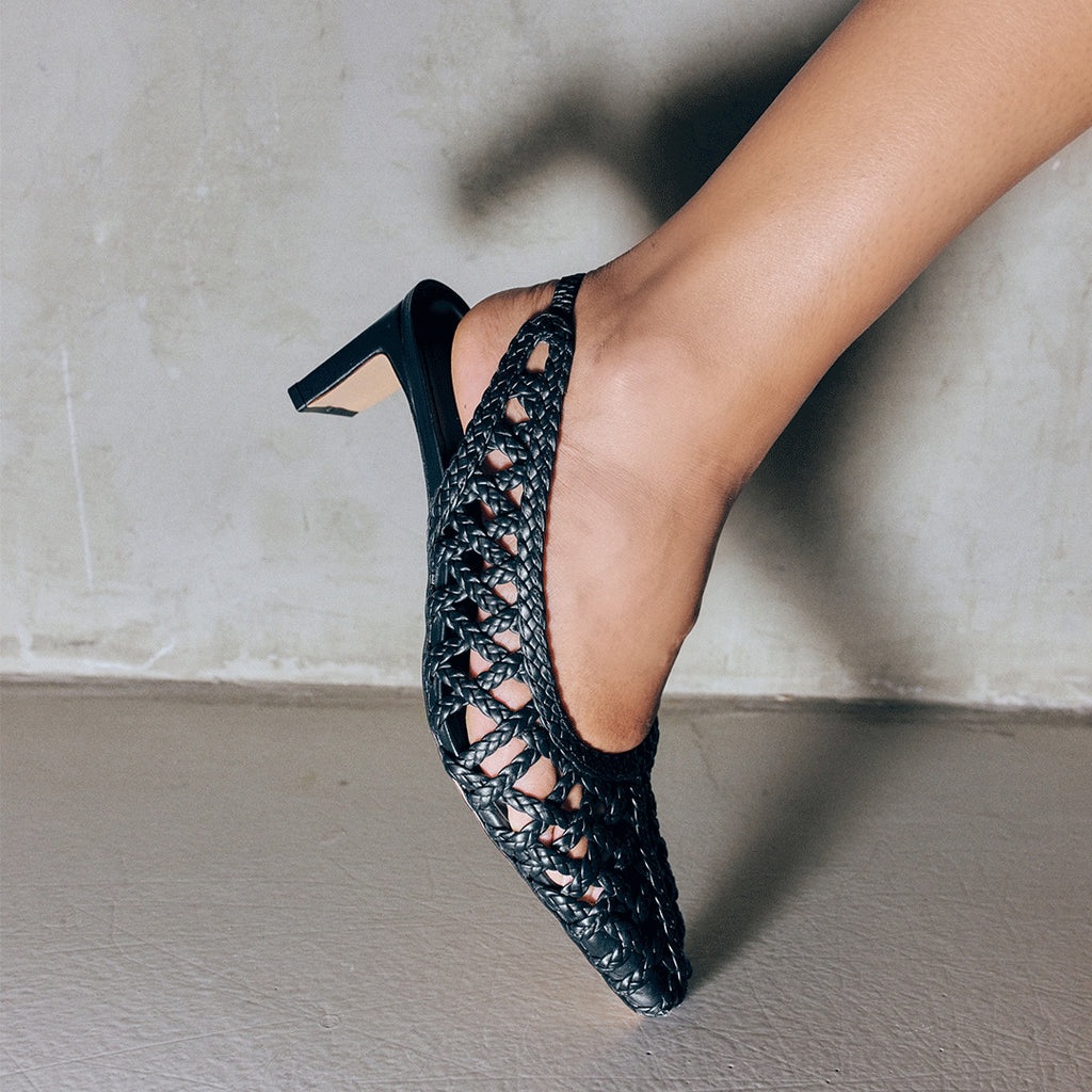 Side angle of Cora black braided leather slingback heel being worn, highlighting the open weave detail and slim heel.


