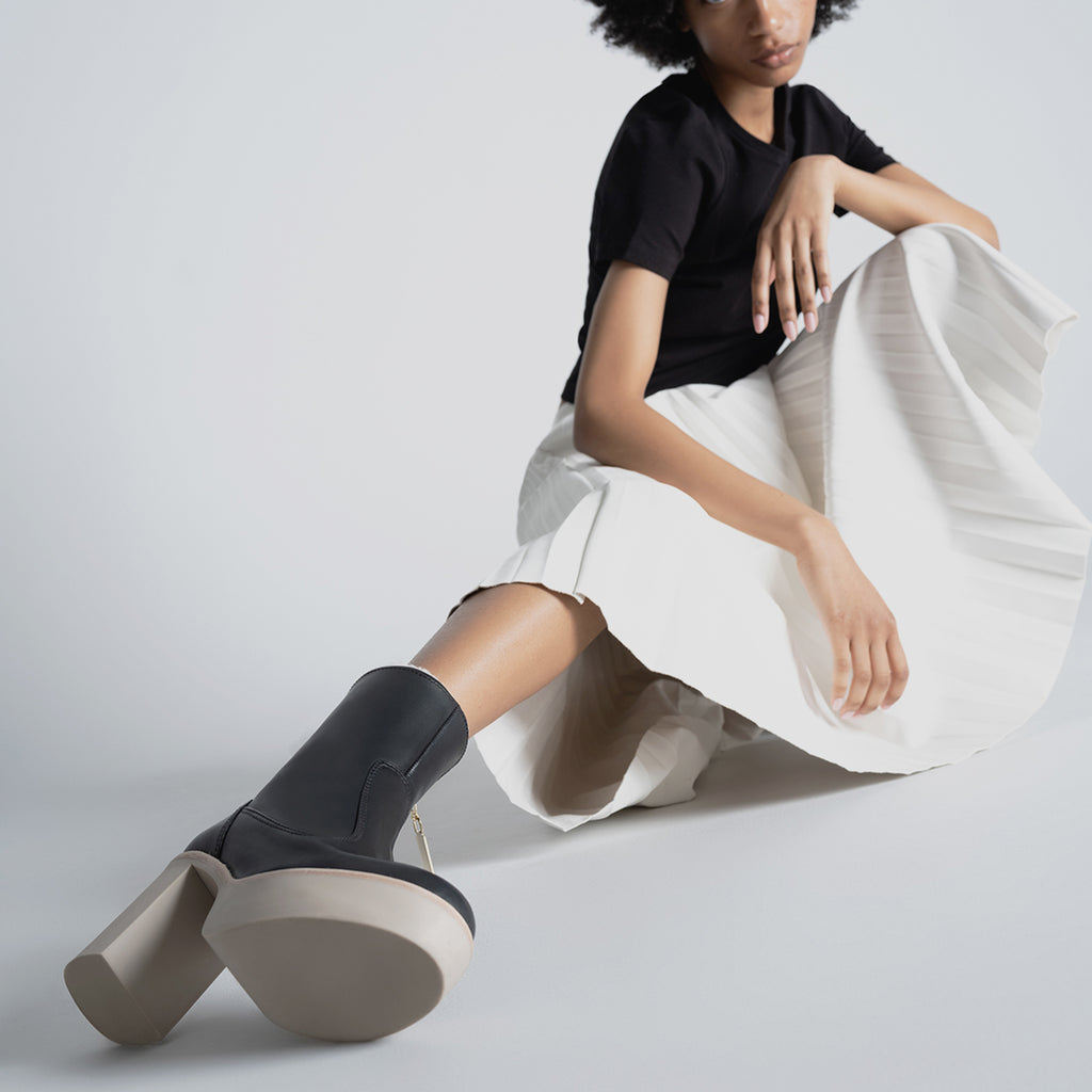 Daniella Shevel Aspen Shearling Boot in black waterproof and weatherproof with rubber lugg sole with white proenza skirt