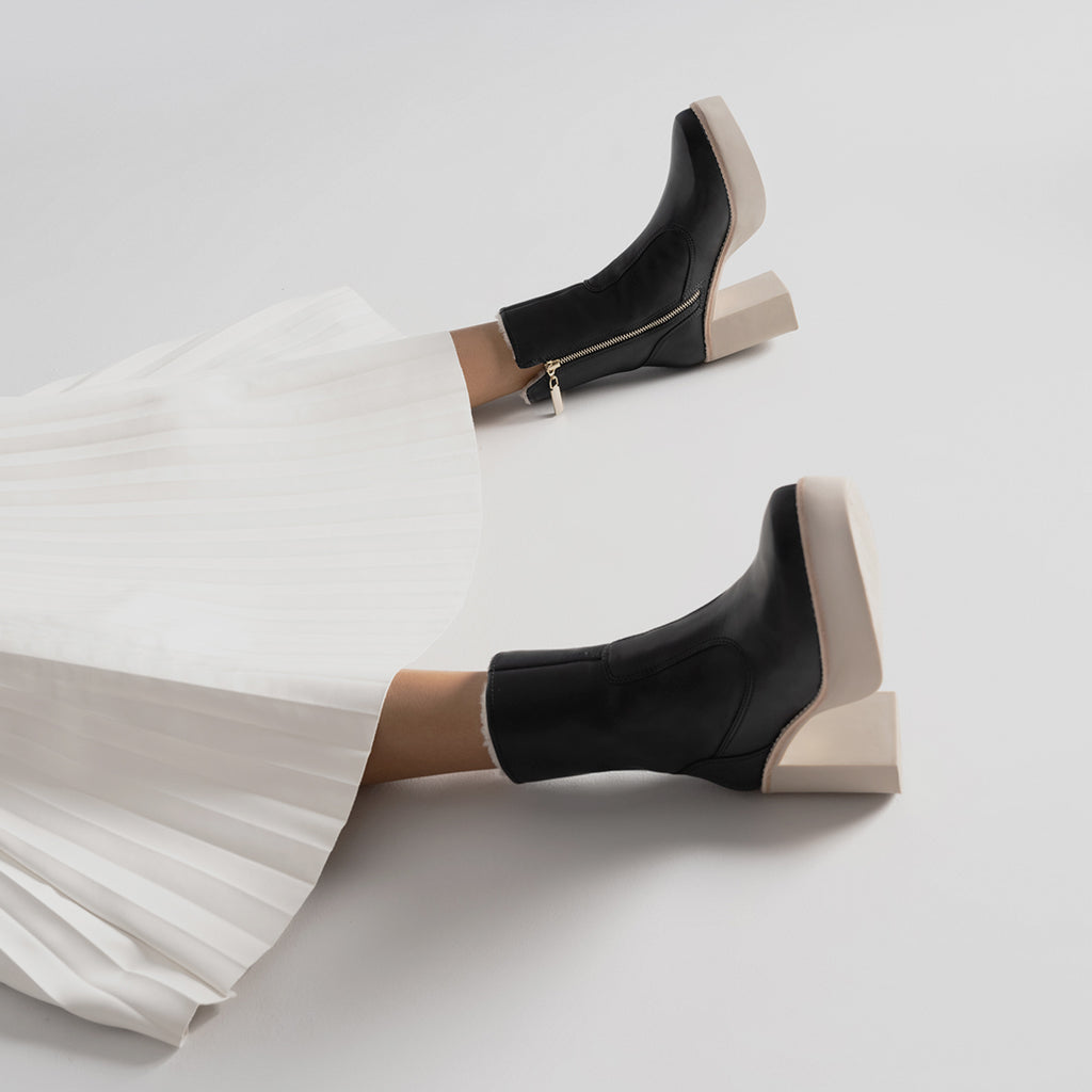 Daniella Shevel Aspen Shearling Boot in black waterproof and weatherproof with rubber lugg sole with white pleated skirt
